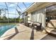Relaxing pool area with screened enclosure, patio furniture, and lush landscaping at 13791 Palmetto Point Ct, Port Charlotte, FL 33953
