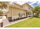 Side view of tan three-story townhome showcasing landscaping and building details at 8269 Enclave Way # 103, Sarasota, FL 34243