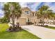 Tan three-story townhome with two-car garage and lush landscaping, featuring palm trees at 8269 Enclave Way # 103, Sarasota, FL 34243