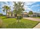 House exterior showcasing a three-car garage, lush lawn, and palm trees at 5514 69Th E Pl, Ellenton, FL 34222