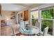 Bright dining area with glass table and four white chairs near a sliding glass door at 3413 Clark Rd # 114, Sarasota, FL 34231