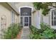 Inviting home entrance featuring a secure screen door, large transom window, and beautiful, verdant landscaping at 7217 Churston Ln, University Park, FL 34201