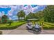 Golf cart on paved path, lush landscaping, palm trees, and a scenic water view at 7217 Churston Ln, University Park, FL 34201