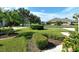 Front yard featuring manicured landscaping, green grass, and a partial view of the house at 4072 Fairway Pl, North Port, FL 34287