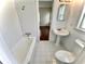 Bathroom with white tile, bathtub, pedestal sink, and toilet at 5817 28Th Avenue E Dr, Bradenton, FL 34208