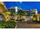 Luxury condo building at night with palm trees and a paved driveway at 2251 Gulf Of Mexico Dr # 301, Longboat Key, FL 34228