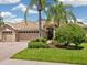 Tan two-car garage home with lush landscaping and brick pavers at 6747 Coyote Ridge Ct, Bradenton, FL 34201