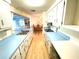 Long view of kitchen with light blue countertops and wood floors at 2434 Fourwind St, Port Charlotte, FL 33948