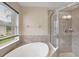 A bright bathroom featuring a large shower and a garden tub next to a sunny window at 11492 Dancing River Dr, Venice, FL 34292