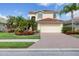Charming home with manicured lawn, colorful flowers, and a red tile roof, creating curb appeal at 11492 Dancing River Dr, Venice, FL 34292