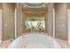 Spa-like bathroom featuring a large, round soaking tub and a window view at 3218 Signet Ct, Sarasota, FL 34240
