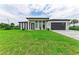 Modern house with a gray garage door and green lawn at 13457 Drysdale Ave, Port Charlotte, FL 33981