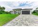 Modern house with a gray garage door and green lawn at 13457 Drysdale Ave, Port Charlotte, FL 33981