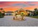 Home's exterior featuring a grand entrance and lush landscaping at sunset at 17812 Doe Creek Ct, Parrish, FL 34219