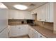 Efficient galley kitchen with white cabinets and granite countertops at 19 Whispering Sands Dr # 204, Sarasota, FL 34242