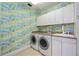 Bright laundry room with patterned walls, washer, dryer, utility sink and storage at 50 Central Ave # 17Phb, Sarasota, FL 34236