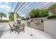 Outdoor kitchen boasts stainless steel gas grill, granite countertops, and dining under a trellis at 50 Central Ave # 17Phb, Sarasota, FL 34236