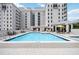 Community pool surrounded by lounge chairs, yellow umbrellas, and tables with chairs on a sunny day at 50 Central Ave # 17Phb, Sarasota, FL 34236