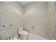 Stylish powder room featuring patterned wallpaper, toilet, and vanity with modern fixtures at 50 Central Ave # 17Phb, Sarasota, FL 34236