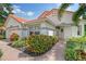 White house with terracotta tile roof, landscaped yard, and brick walkway at 5814 Fairwoods Cir, Sarasota, FL 34243