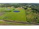 Aerial view of property highlighting home, pond, and surrounding fields at 23800 Jennings Rd, Myakka City, FL 34251