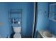 Bright blue bathroom with a toilet, shelving, towel rack, and sink vanity with cabinet storage at 6064 Shearwater Dr, Englewood, FL 34224