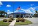 Community clubhouse featuring an American flag, ample parking, and well-maintained landscaping at 6064 Shearwater Dr, Englewood, FL 34224