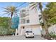 Stunning three-story home showcasing a two-car garage, glass-block windows, and lush landscaping with palm trees at 648 Beach Rd, Sarasota, FL 34242