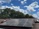 Solar panels are installed on a red-shingled roof on a sunny day with bright blue skies and white clouds at 906 Tropical Dr, Bradenton, FL 34208