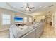 Comfortable living room open to kitchen with tray ceilings, ceiling fan, tile floor and beach view on the TV at 12198 Longview Lake Cir, Bradenton, FL 34211