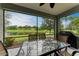 A screened patio has seating and a grill with views of the backyard and pond at 12198 Longview Lake Cir, Bradenton, FL 34211