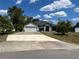 Charming single-story home featuring a wide driveway, attached garage, and lush tropical landscaping under a bright blue sky at 2204 Chipley Ave, North Port, FL 34286