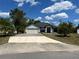 Charming single-story home featuring a wide driveway, attached garage, and lush tropical landscaping under a bright blue sky at 2204 Chipley Ave, North Port, FL 34286