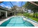 A beautiful screened in pool with clear blue water, plants, and backyard seating at 2204 Chipley Ave, North Port, FL 34286
