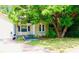 Cozy single-story house featuring light yellow siding and a mature tree providing shade in the front yard at 5415 5Th N Ave, St Petersburg, FL 33710