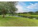 Serene lakefront view with lush green grass and large oak tree at 12198 Longview Lake Cir, Bradenton, FL 34211