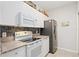 Updated kitchen with white cabinets, granite countertops, and black appliances at 5122 Northridge Rd # 107, Sarasota, FL 34238