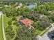 Aerial view of a home with a terracotta roof, solar panels, screened pool, and mature trees at 7602 Partridge Street Cir, Bradenton, FL 34202