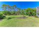 Expansive backyard featuring lush green grass and landscaping with tall trees, providing ample space for outdoor activities at 7602 Partridge Street Cir, Bradenton, FL 34202