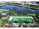 Aerial view of a community bocce ball court with palm trees and a lake at 13212 Deep Blue Pl, Lakewood Ranch, FL 34211