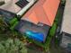 Aerial view of a home featuring a screened-in pool, lush landscaping, and a distinctive red tile roof at 7623 Birds Eye Ter, Bradenton, FL 34203