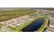 Aerial view of the backyard featuring manicured grass, a covered patio, and views of the pond beyond at 9478 Tequila Sunrise Dr, Sarasota, FL 34241