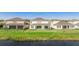 A view of the backyard featuring manicured grass, a covered patio, and views of the pond beyond at 9478 Tequila Sunrise Dr, Sarasota, FL 34241