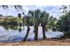 Waterfront view featuring palm trees by the water on a partly cloudy day at 2708 Starlite Ln, Port Charlotte, FL 33952