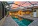 Resort-style pool with covered patio, brick pavers, and large urns at sunset at 909 Macewen Dr, Osprey, FL 34229