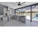 Outdoor kitchen with stainless steel appliances and granite countertops, adjacent to a screened pool area at 14312 Barbarossa Ln, Port Charlotte, FL 33981