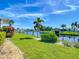 Landscaped backyard with canal view, lush lawn, and palm trees at 193 Carlisle Nw Ave, Port Charlotte, FL 33952