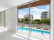 Bright living room featuring large windows with a view of the community pool and surrounding buildings at 111 Golden Gate Pt # 201, Sarasota, FL 34236