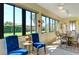 Sunroom with blue armchairs, wooden table and backyard view at 1130 Cielo Ct, North Venice, FL 34275