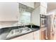 Kitchen sink with window, subway tile backsplash, stainless steel appliances, and overhead glass storage at 1533 1St Ave W Dr, Bradenton, FL 34205